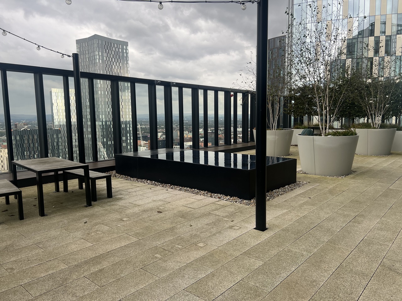 Rooftop terrace with outdoor tables, planters, a water feature and city views