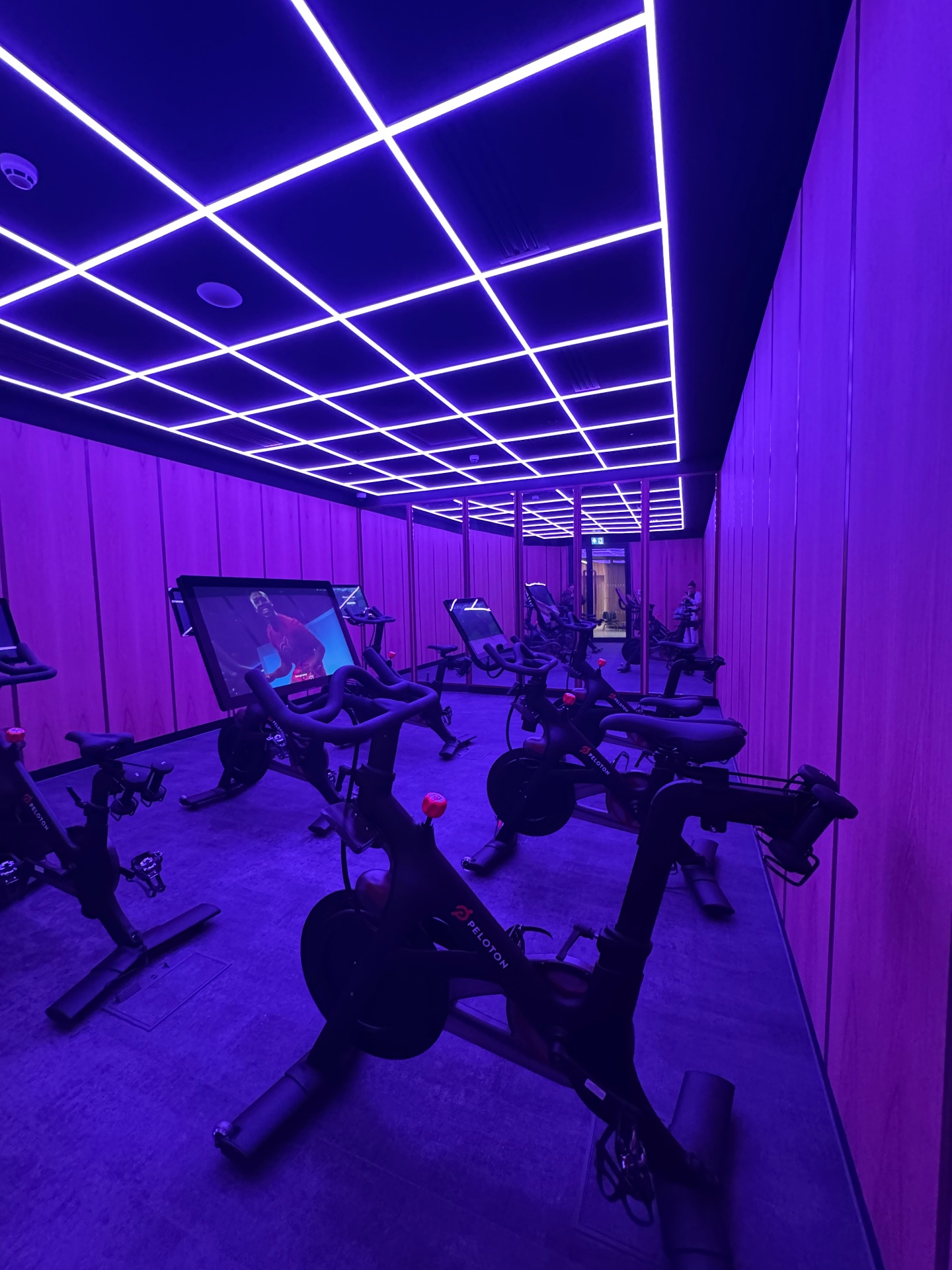 Peloton spin studio with bikes, mirror wall and feature lighting