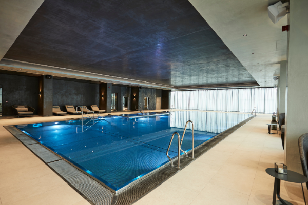 Indoor swimming pool with underwater lighting, entry steps and poolside lounge seating