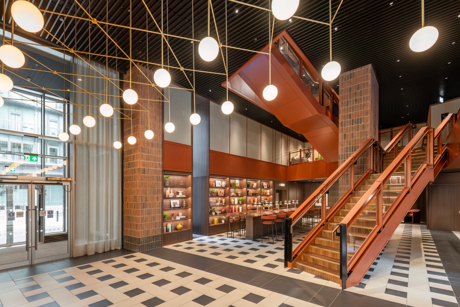 Double-height lobby with a feature staircase, globe pendant lighting and a checkered floor
