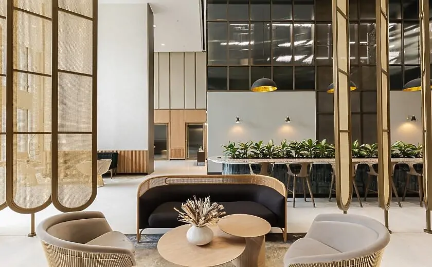 Lounge seating with armchairs and a curved sofa beside a terrazzo bar counter with planted greenery