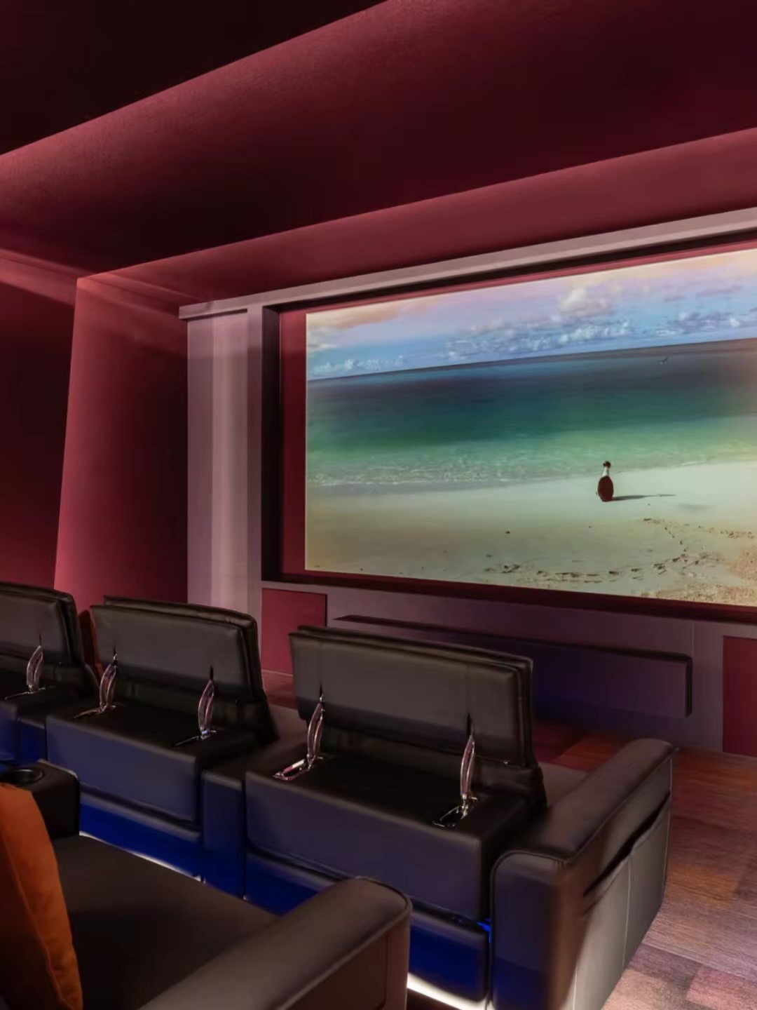 Cinema room with a large screen and rows of reclining seats