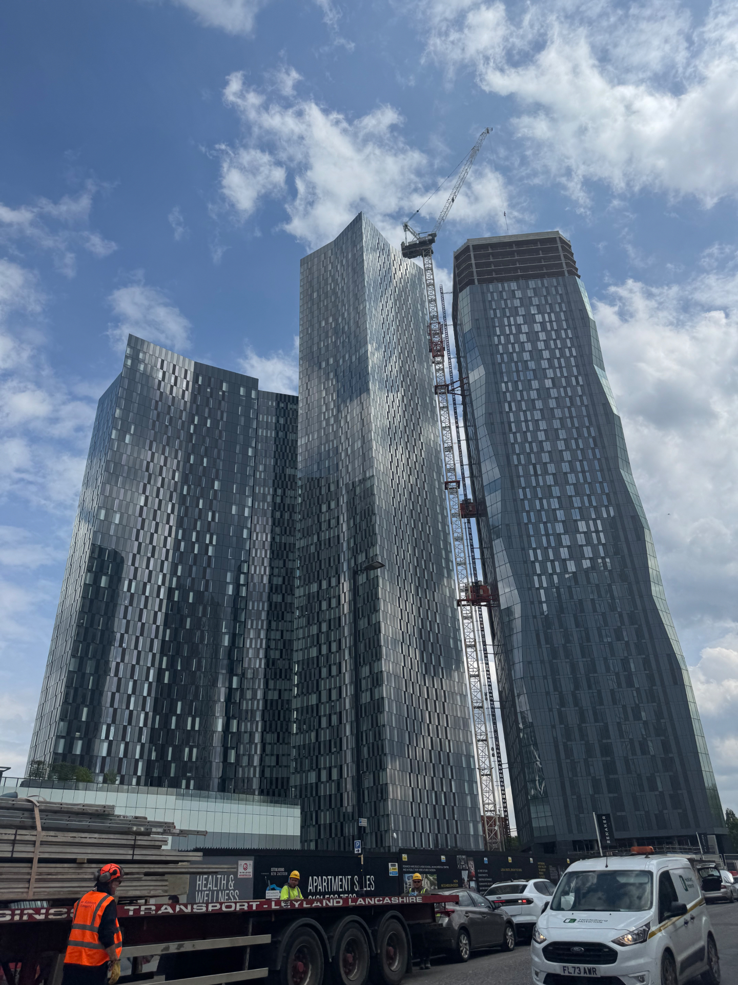 Street-level view of the glass towers at Deansgate Residences in New Jackson, with construction continuing on the right-hand tower