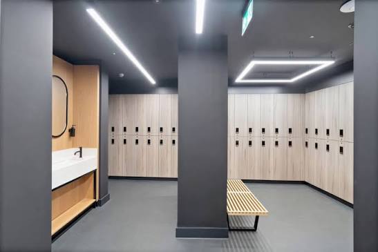 Changing room with wooden lockers, a vanity sink and bench seating
