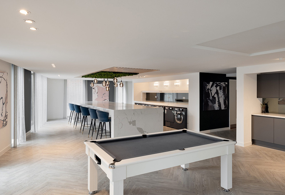 Games lounge with a pool table, the residents’ kitchen island and laundry beyond