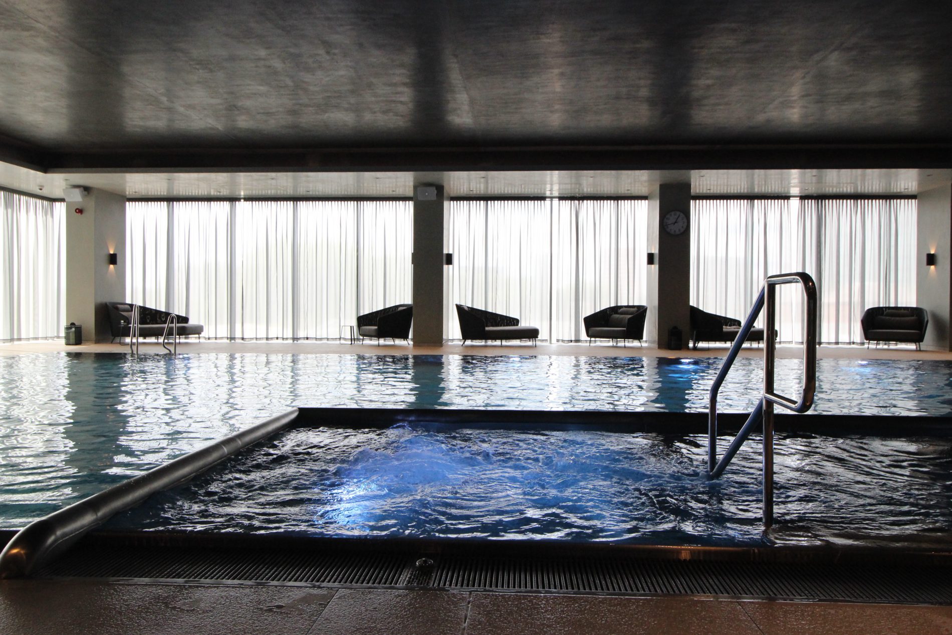 Bubbling hydrotherapy spa in the foreground, with the swimming pool and lounge seating beyond