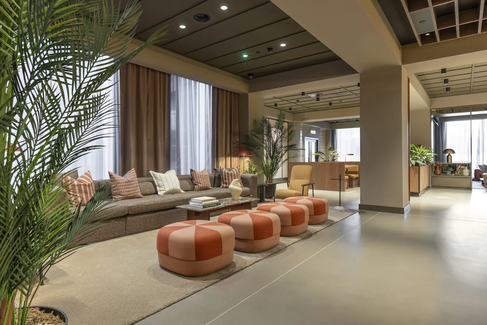 Residents’ lounge with sofas, patterned poufs and indoor planting