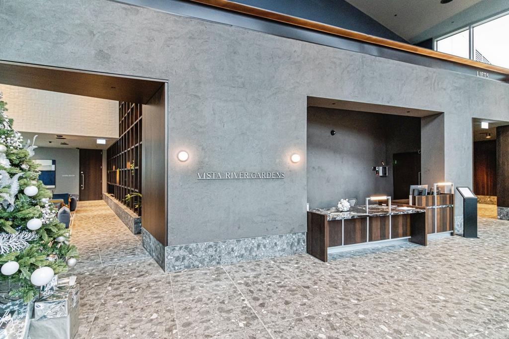 Entrance lobby with Vista River Gardens wall signage, a reception desk, terrazzo floor and a decorated Christmas tree