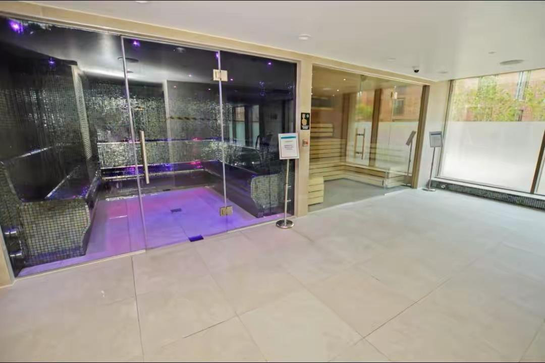 Spa suite with a wooden sauna cabin and a dark-tiled heated water suite under purple lighting