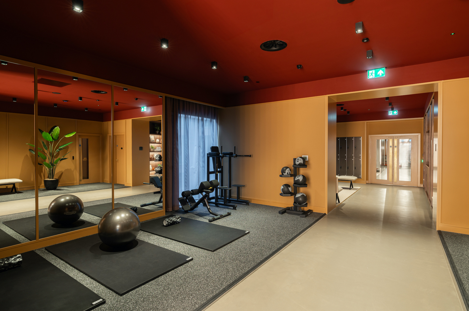 Fitness studio with gym balls, a weights rack, exercise mats and a mirror wall