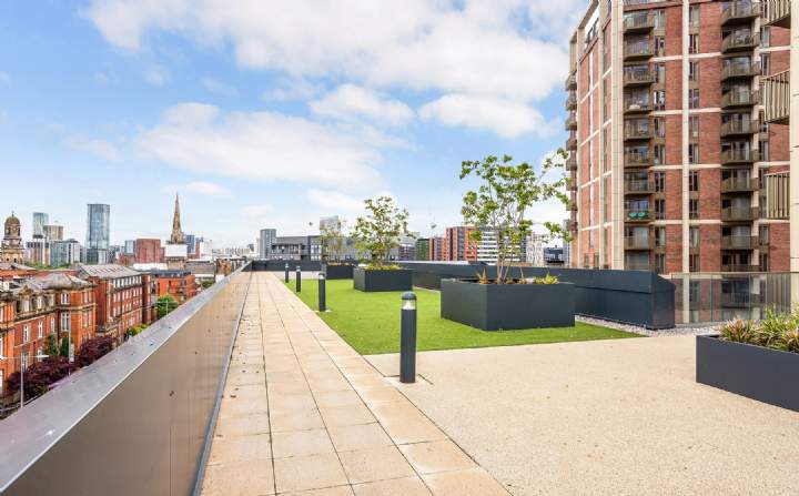 Roof terrace with planters, lawn, tree planting and city views over Salford and Manchester