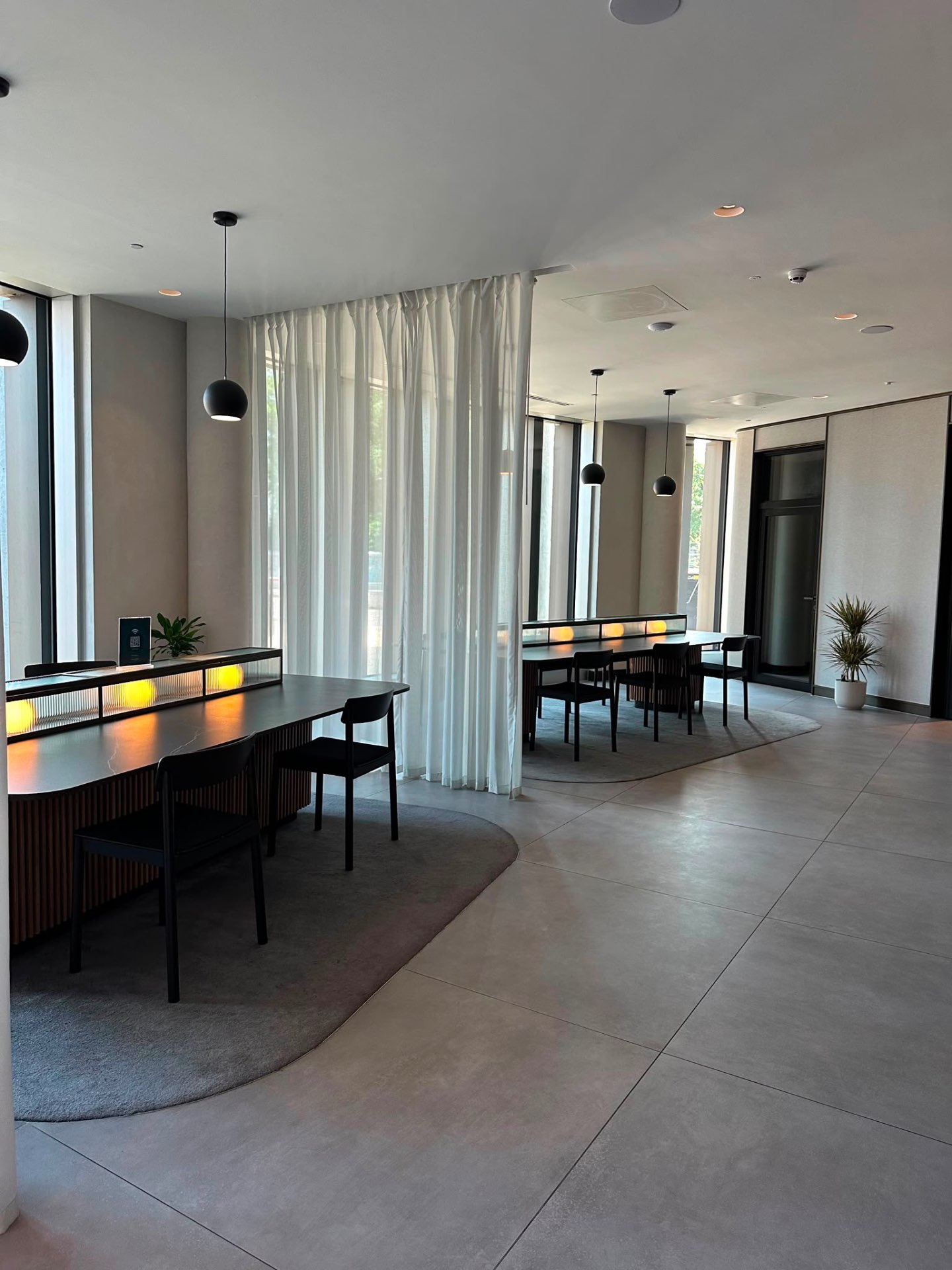 Communal tables with seating beneath pendant lights