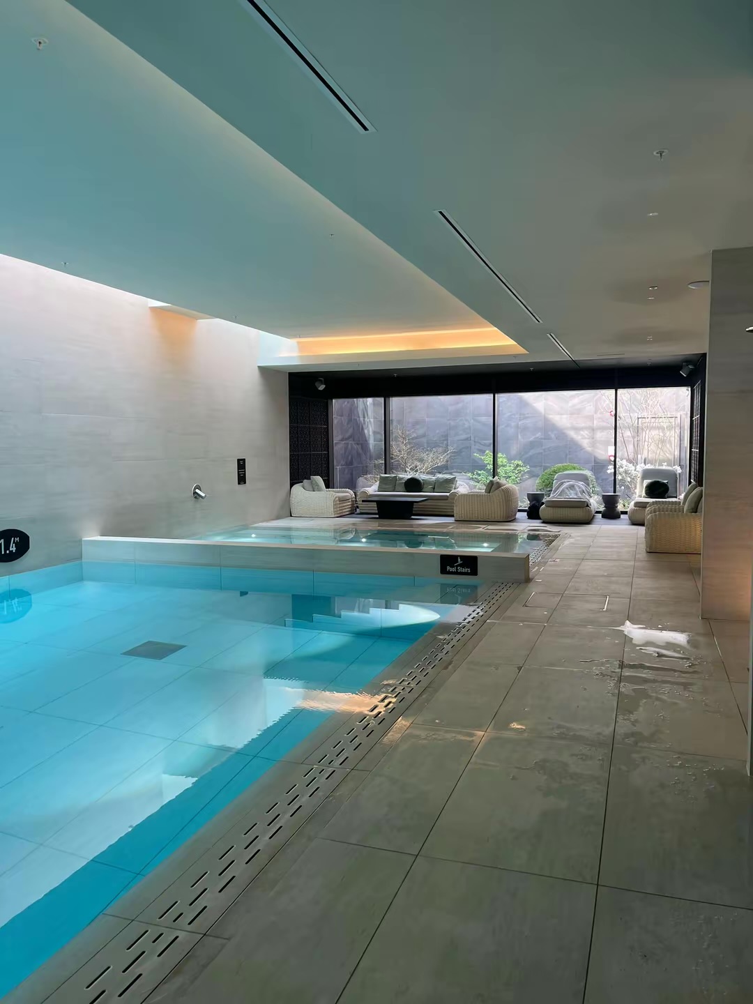 Indoor swimming pool with steps and poolside lounge seating