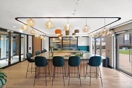 High-top terrazzo island with counter stools and pendant lighting, opening onto an outdoor terrace