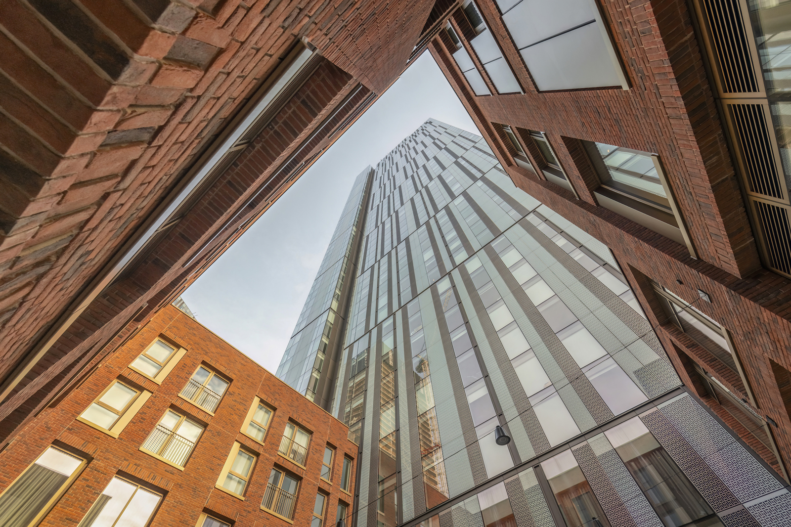 The Cortland tower rising above the red-brick Colliers Yard buildings, seen from street level