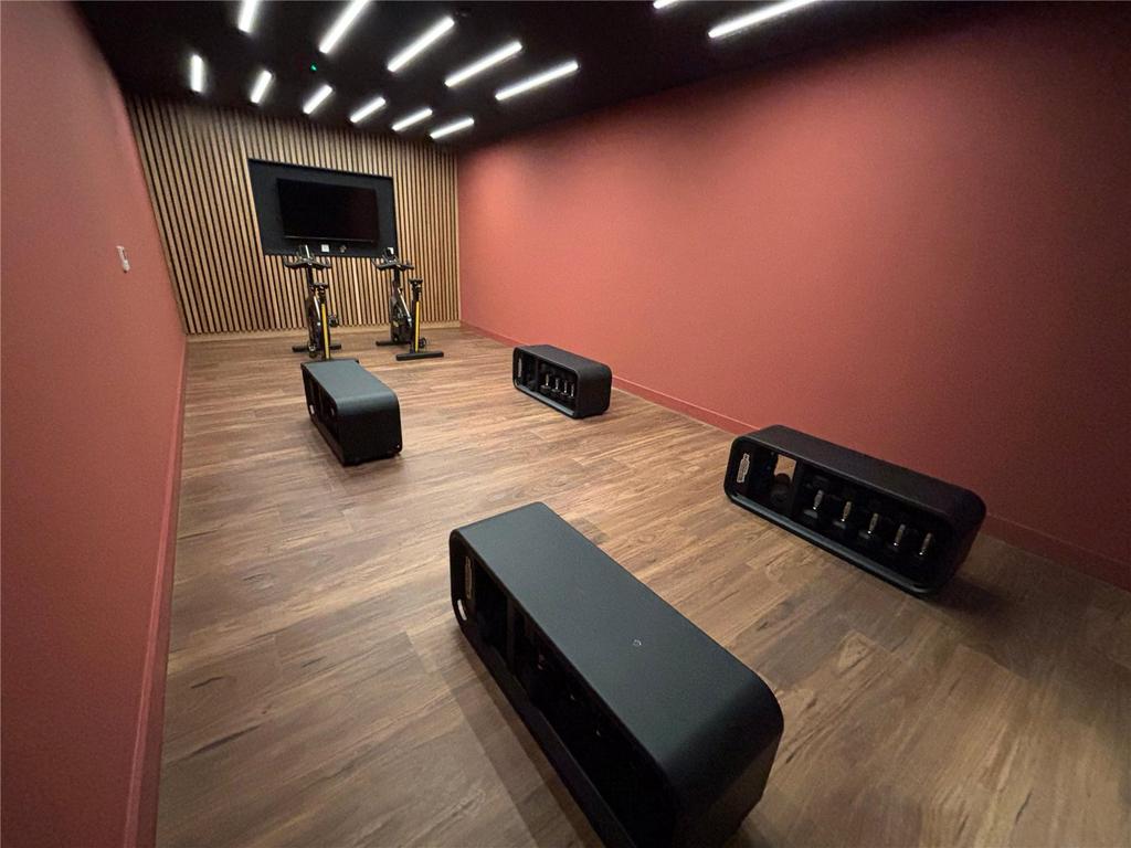 Workout benches, two spin bikes and a wall-mounted screen in a wood-panelled studio