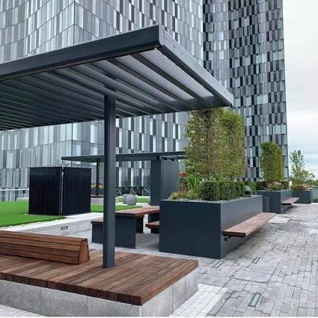 Covered pergola seating area on the rooftop terrace with benches, planters and views of the towers