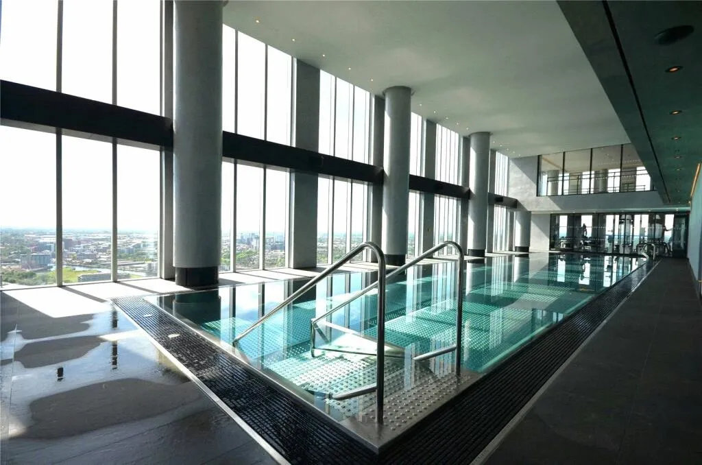 Indoor 44th-floor swimming pool alongside floor-to-ceiling windows with city views