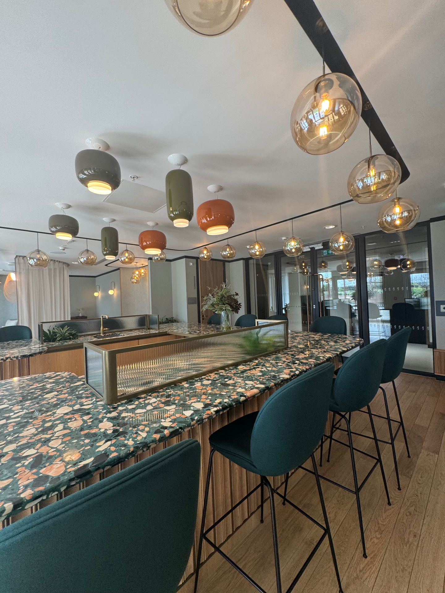 Communal bar with terrazzo counter, bar stools and pendant lighting