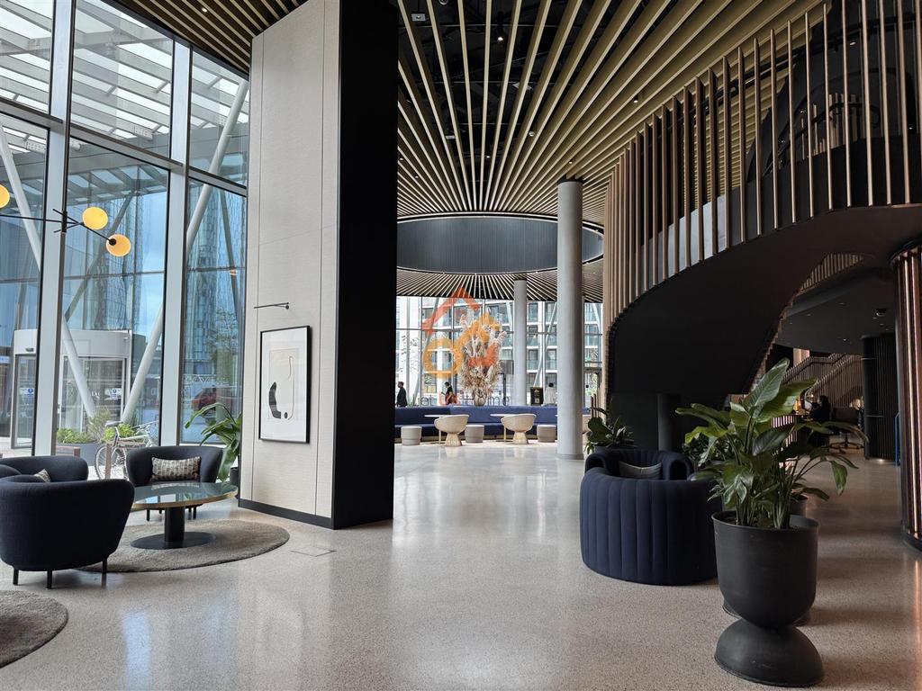 Double-height entrance lobby with a curved timber staircase, lounge seating and full-height glazing