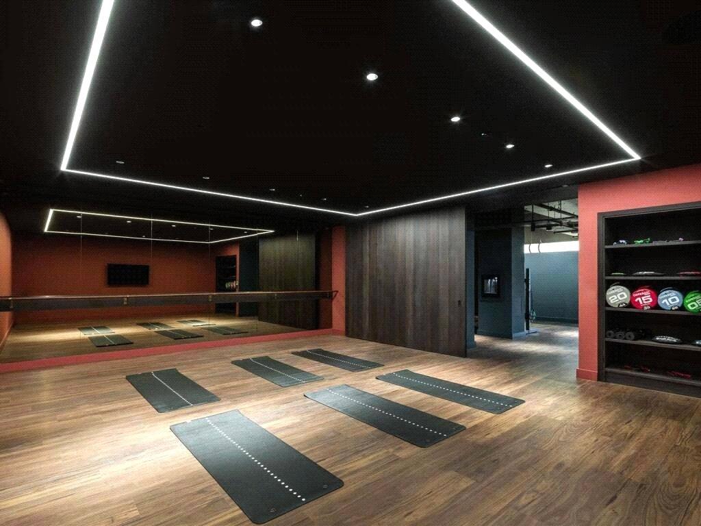 Studio with exercise mats laid out, a mirrored wall with ballet barre and shelves of medicine balls